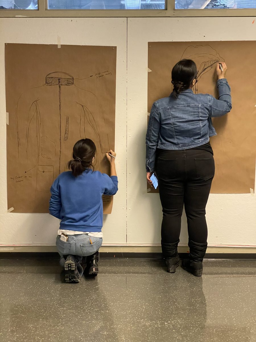 Two students sketching concepts at life size on large kraft paper sheets